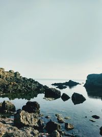 Rocks on beach against clear sky