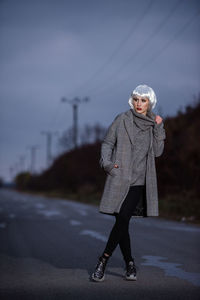 Full length portrait of woman standing on road during winter