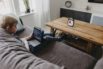 Boy spending time with laptop according to clock