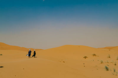 People in desert against sky