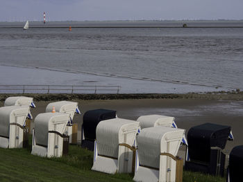 Hooded chairs on beach against sky