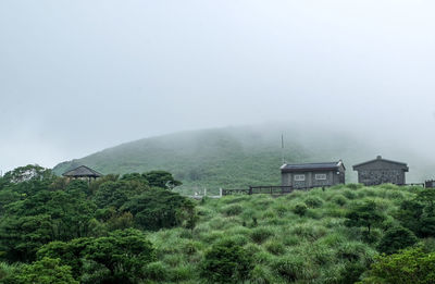 House by trees and mountains against sky