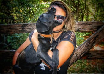 Woman with dog sitting in forest