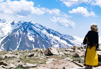 Rear view of woman standing on snowcapped mountain