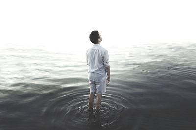 Rear view of man standing in water