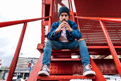 Full length portrait of young man sitting outdoors