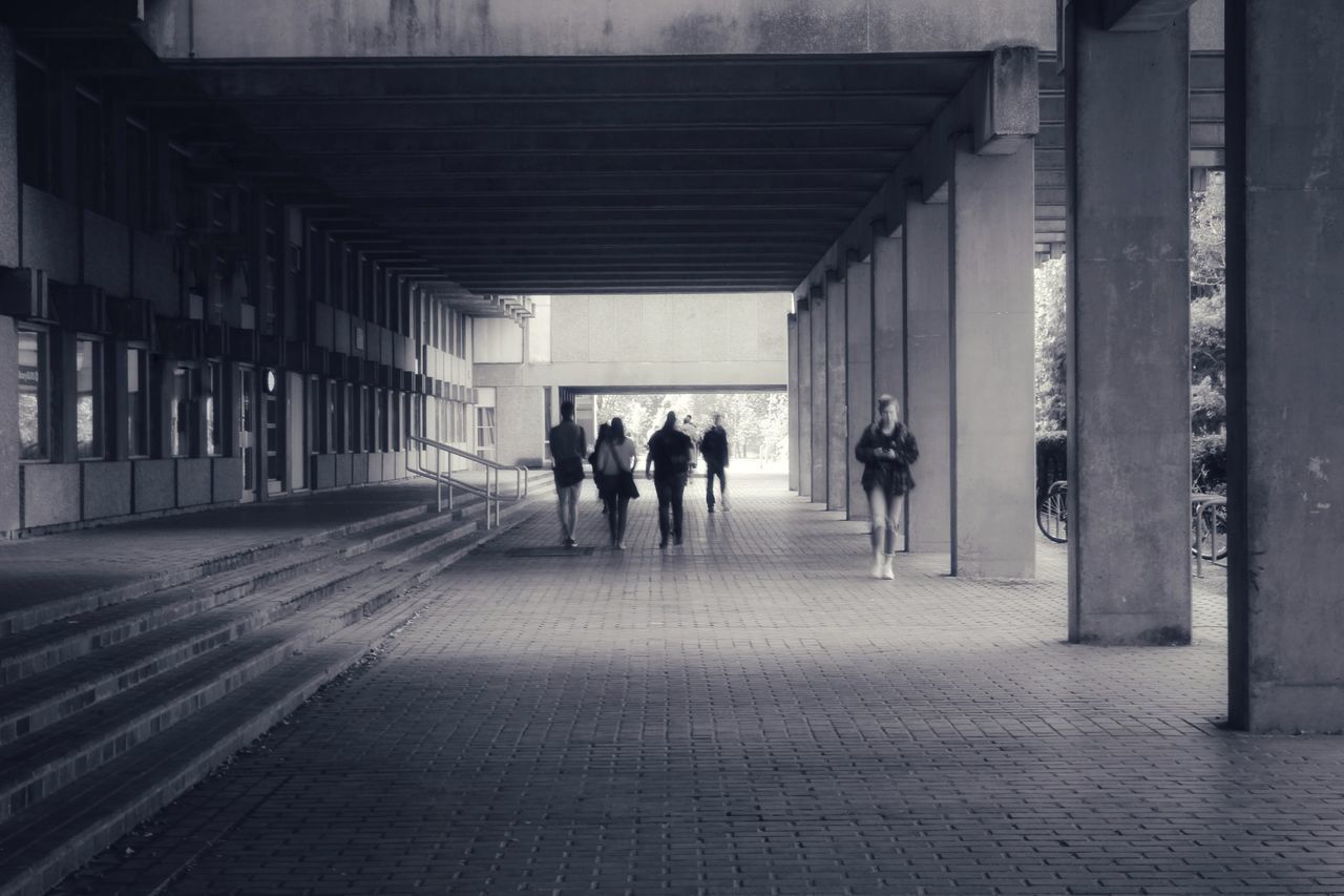 REAR VIEW OF PEOPLE WALKING ON FOOTPATH IN BUILDING