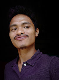 Portrait of young man against black background