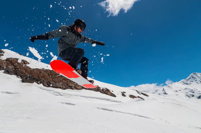 Rear view of man skiing on snowcapped mountain against sky