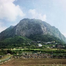 Scenic view of agricultural field by mountains against sky