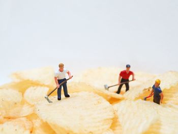 Close-up of figurines on potato chips against white background