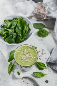 Glass of homemade healthy green smoothie with fresh baby spinach