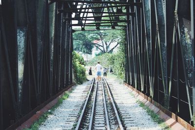Rear view of man on railroad tracks under bridge