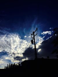 Low angle view of power lines against cloudy sky