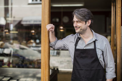 Thoughtful salesman looking away at supermarket entrance