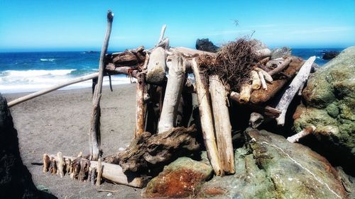 Wooden log on beach against sky