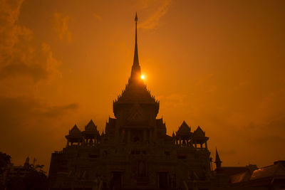 Low angle view of buddhist temple against orange sky