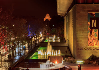 Illuminated buildings by canal at night