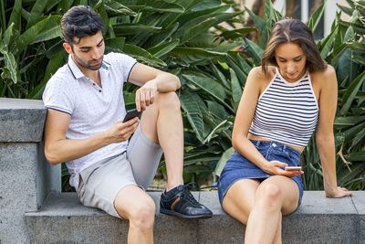 Full length of young couple sitting outdoors