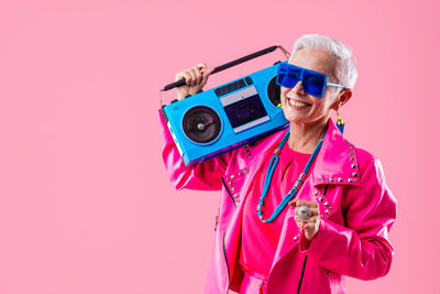 Portrait of young woman wearing sunglasses against pink background