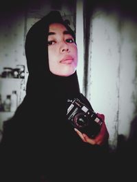 Portrait of beautiful young woman holding camera