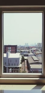 Buildings against clear sky seen through glass window