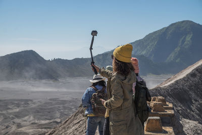 Woman taking selfie with friends against mountains