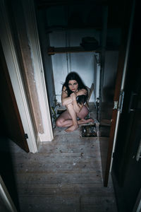 Portrait of woman sitting on door at home
