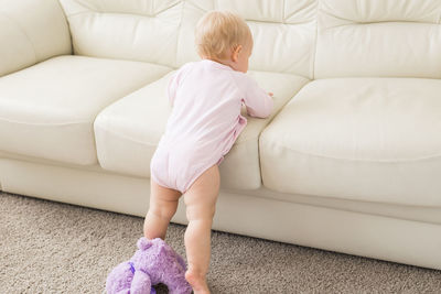 Full length of cute baby girl on sofa at home