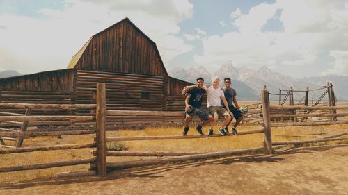 Full length of men working on wood against sky