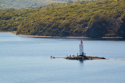 Lighthouse by sea against mountain