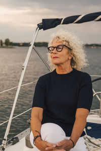 Senior woman with eyes closed sitting on boat during sunset