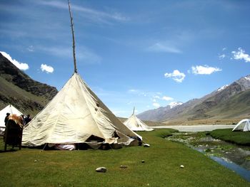 Tents on grass against sky