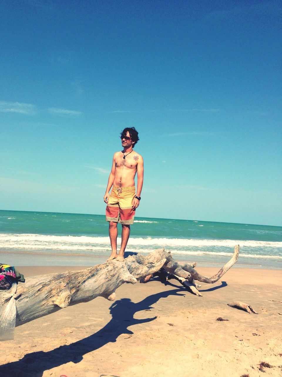 beach, sea, horizon over water, sand, shore, water, lifestyles, leisure activity, full length, sunlight, casual clothing, sky, vacations, blue, clear sky, standing, nature, tranquility