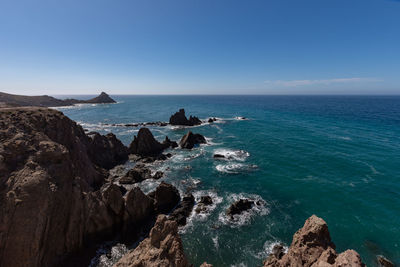 Scenic view of rocks in sea against blue sky