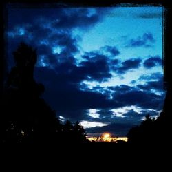 Silhouette of trees against cloudy sky