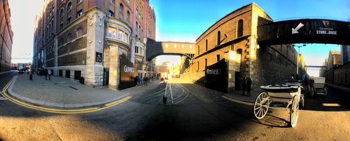 Cars on road by buildings against sky in city