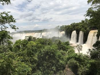 Scenic view of waterfall in forest against sky