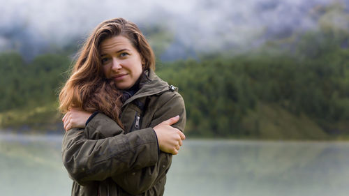 A young beautiful tourist walks along boards through a stormy mountain stream