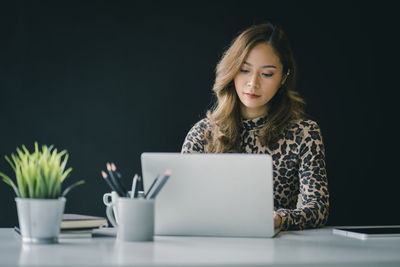 Young woman using smart phone while sitting on table