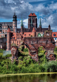 River and historic buildings against cloudy sky