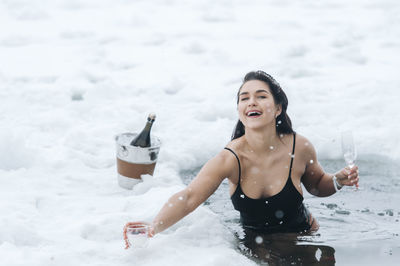 Smiling woman holding wineglass standing in frozen lake