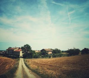 Road by houses against sky