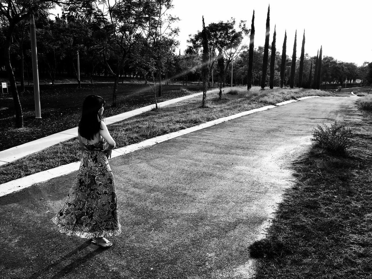 REAR VIEW OF WOMAN STANDING ON FOOTPATH