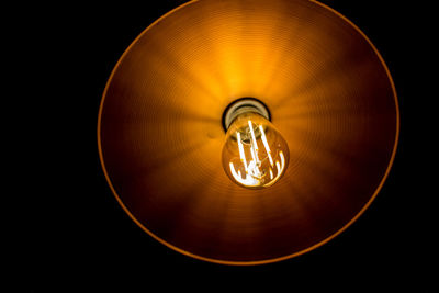 Low angle view of illuminated light bulb against black background