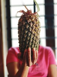 Woman with face covered by pineapple