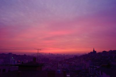 Cityscape against dramatic sky during sunset