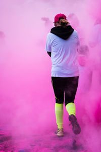Rear view of woman walking on road in pink powder paint