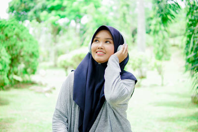 Portrait of young woman standing against trees