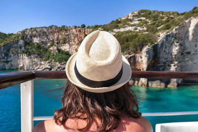 Rear view of woman wearing hat by railing against mountain